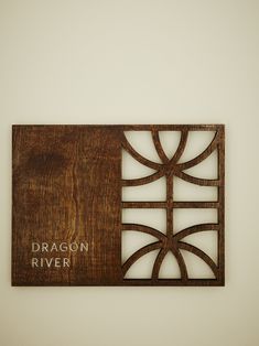 a wooden plaque that reads dragon river on it's side with an intricate design