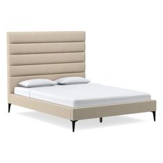 an upholstered bed frame with white sheets and pillows on the headboard is shown