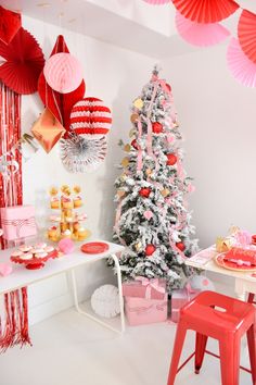 a decorated christmas tree in a room with red and pink decorations hanging from the ceiling