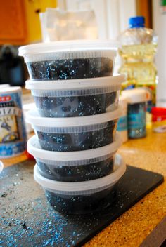 plastic containers stacked on top of each other on a counter with food in the background