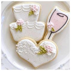 decorated cookies in the shape of heart and wedding dress on a white plate with pink flowers