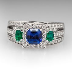 This mesmerizing ring features one (1) prong set cushion cut natural sapphire, two (2) prong set emerald cut natural emeralds, and seventy (70) prong set round brilliant cut diamonds. The ring measures 9.1mm at the top and rises 8.0mm above the finger, tapering to 4.4mm wide and 1.6mm thick at the base of the shank. It is crafted in 18k white gold and is currently a size 7.5. Luxury Multi-stone Emerald Cut Emerald Ring, Formal Multi-stone Emerald Cut Sapphire Ring, Emerald-cut Multi-stone Diamond Emerald Ring, Emerald Cut Emerald Ring With Multi-stone Diamond, Elegant Multi-stone Sapphire And Emerald Ring, Emerald-cut Sapphire Multi-stone Jewelry, Emerald Cut Sapphire Multi-stone Jewelry, Multi-stone Platinum Jewelry With Emerald Cut, Emerald Cut Multi-stone Emerald Jewelry