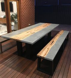 two benches sitting on top of a wooden floor next to a brick wall and window