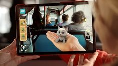 a person holding up a tablet with a small stuffed animal on it