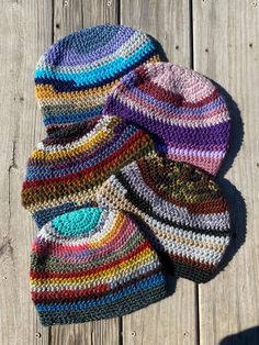 three knitted hats sitting on top of a wooden floor