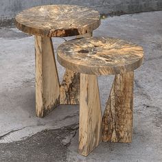 two wooden stools sitting next to each other on the cement floor in front of a building