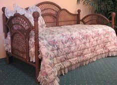 the bed is made with wicker and has pink floral bedspread on it