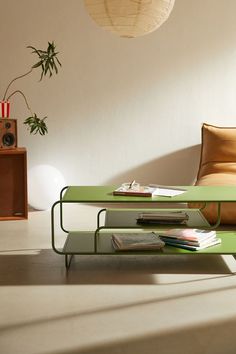 a green coffee table sitting on top of a white floor next to a chair and lamp