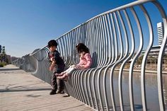 two children are sitting on a metal fence