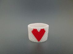 a small white and red beaded bracelet with a heart on it's side