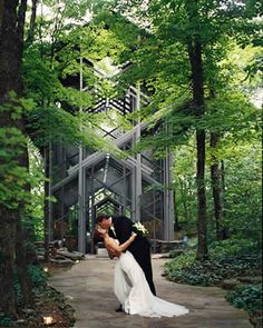 a bride and groom kissing in front of a structure that looks like a tree house