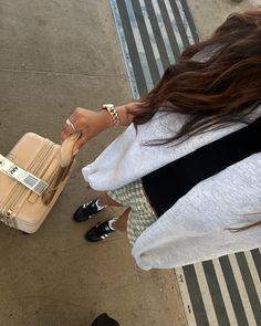 a woman holding onto a piece of luggage on the ground next to another person's legs