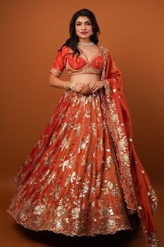 Rust orange flared lehenga with all over gold toned sequin gullista embroidery. Paired with a half sleeves choli style embroidered blouse and a cutwork border sequin bloom embroidered dupatta. - Aza Fashions Dark Orange Lehenga, Orange Choli With Pallu For Festivals, Traditional Drape Orange Choli For Navratri, Traditional Orange Choli For Navratri, Orange Choli With Zari Work For Festivals, Orange Choli With Sheer Dupatta For Navratri, Orange Georgette Traditional Wear For Navratri, Orange Sharara With Sheer Dupatta For Navratri, Orange Bollywood Set With Sheer Dupatta