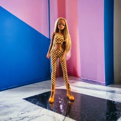 a barbie doll is standing on a black and white checkerboard floor with her legs crossed