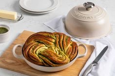 a pan filled with bread sitting on top of a wooden cutting board next to a knife