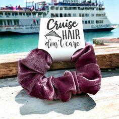 a purple scrunchy hair tie sitting on top of a wooden table next to the ocean