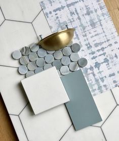 some white and grey tiles with a gold bowl on top of them, next to a wallpaper