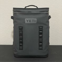 a grey yeti backpack sitting on top of a black table next to a white wall