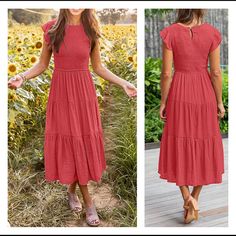 a woman in a red dress standing on a wooden deck next to sunflowers