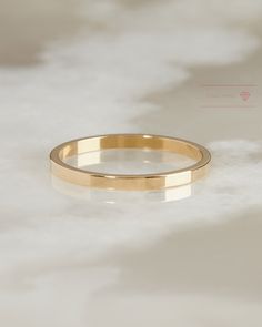 a gold wedding ring sitting on top of a white surface