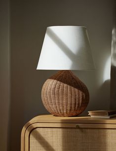 a table lamp sitting on top of a wooden dresser next to a white lampshade