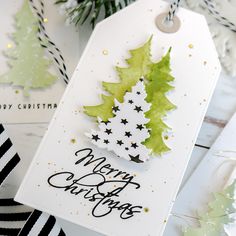 a christmas card with green and white trees on it, sitting next to other cards