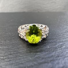 A stunning 9ct white gold vintgage peridot and diamond ring featuring a large ocal cut beautifully faceted green peridot gemstone claw set with each side flanked by a small round cut diamond leading on to a very fancy filigree design scrolling ornate open shoulders blended to a smooth tapering band. Birmingham Hallmarks. The ring is a UK size N - US Size 6.75 which can be resized a few sizes. Elegant Lime Green Oval Rings, Oval Peridot Gemstones For Anniversary, Oval Lime Green Rings For Anniversary, Lime Green Oval Rings For Anniversary, Classic Lime Green Oval Jewelry, Lime Green Oval Rings With Accent Stones, Oval Lime Green Anniversary Ring, Lime Green Oval Rings Fine Jewelry, Oval Lime Green Fine Jewelry Ring