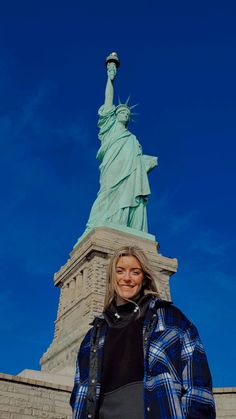 a woman standing in front of the statue of liberty