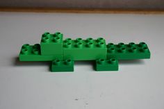 four green legos sitting on top of a white table next to eachother