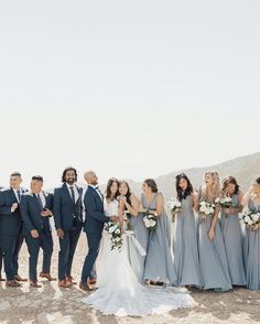 a group of people standing next to each other on top of a dirt field with mountains in the background