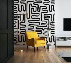 a yellow chair sitting in front of a tv on top of a wooden floor next to a black and white wall