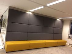 a yellow bench sitting in front of a flat screen tv on a wall mounted to the side of a wall