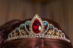 a woman wearing a tiara with red and blue stones