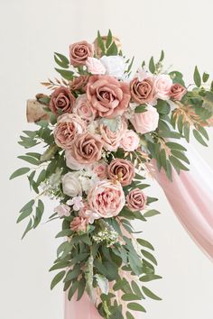 a bouquet of pink roses and greenery is hanging from the side of a chair