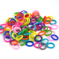 a pile of multicolored plastic rings on a white surface with one ring in the middle