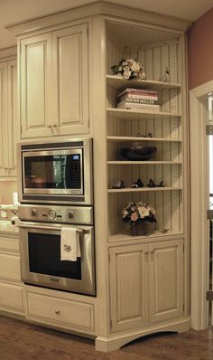 a kitchen with an oven, microwave and bookcases in it's center