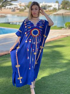 This beautiful Kaftan with the Siwa inspired embroidery is a bohemian and flashy dress that will catch everyone's eyes. This Kaftan is ideal to wear for any casual occasion. Whether taking a trip down the shopping lane, or home-based kitty parties, or about anything else, wearing this dress will make you feel classy and comfortable. Fabric : 70% Egyptian Cotton; 30% Polyester. Size : Free sized dress. This Kaftan is a free sized dress meaning that it comes in one size only that fits any size fro Traditional V-neck Kimono For Summer, Bohemian V-neck Kaftan For Eid, Bohemian Kimono With Intricate Embroidery, Blue Embroidered Dresses For Festivals, Festival V-neck Kaftan With Resham Embroidery, Floral Embroidered Dress For Beach, Bohemian Kimono Tunic For Eid, Bohemian Tunic Kimono For Eid, Bohemian Dresses With Kimono Sleeves For Eid