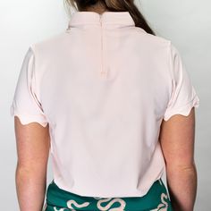 the back of a woman wearing a pink shirt and green skirt with white letters on it