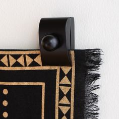 a close up of a black and tan rug on a wall with a button in the middle