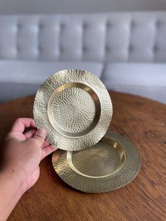 a person holding two plates on top of a wooden table next to a white couch