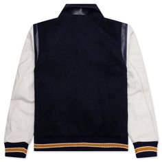 The BTFL Studios Letterman Jacket in Navy exemplifies the brand's commitment to blending heritage with modern design. Crafted from premium Japanese wool with Italian leather details, this jacket offers a luxurious take on the traditional American letterman style. It features a chenille embroidered patch, adding a touch of vintage charm. Each jacket is meticulously made, highlighting BTFL Studios' focus on quality and attention to detail. Premium Japanese wool Italian leather details Chenille emb Designer Winter Varsity Jacket For College, Luxury Winter Outerwear With Contrast Collar, Luxury Wool Outerwear With Ribbed Cuffs, Luxury Navy Peacoat For Fall, Designer Long Sleeve Outerwear For College, Classic Winter Varsity Jacket With Contrast Collar, Luxury Varsity Jacket For Fall Streetwear, Classic Varsity Jacket With Contrast Collar For Winter, Luxury Outerwear With Contrast Collar And Long Sleeves