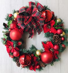 a christmas wreath with red and green ornaments on it, hanging from a white wall