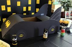 a batman themed birthday party with black and yellow decorations, batmobiles and fruit