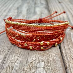 red leather and gold beaded bracelets on wooden surface