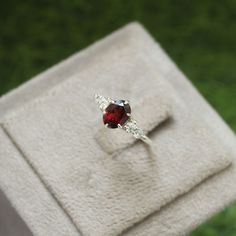 a red and white ring sitting on top of a cloth covered box in the grass