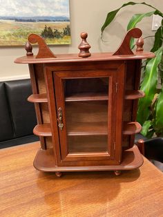 a wooden cabinet sitting on top of a table next to a potted green plant