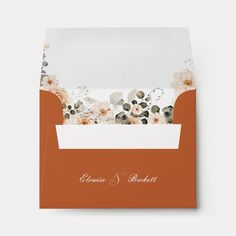 an orange and white wedding card with flowers on the front is folded in a pocket