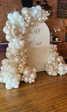 balloons are arranged in the shape of an arch with words on it and white flowers