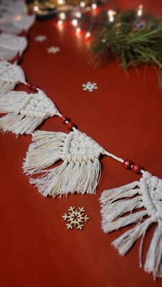 white tassels are hanging on a red tablecloth with christmas decorations and lights in the background