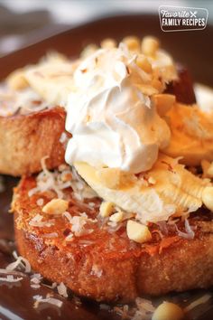 two pieces of toast topped with whipped cream and nuts on a brown plate next to chocolate